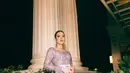 Kebaya berwarna ungu keabuan ini dihiasi dengan detail payet berkilauan yang membalut tubuhnya dengan sempurna, menciptakan efek glamor yang tetap terasa lembut. Potongan lengan panjang dengan aksen ruffle di pergelangan menambah kesan dramatis, sementara belt berwarna perak dengan detail ornamen memberi sentuhan klasik yang semakin memperindah siluetnya.  [@raisa6690].